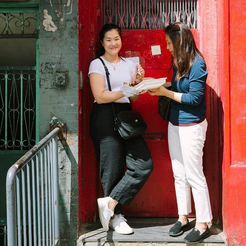 The Woks of Life family members enjoying lunch on a stoop in NYC Chinatown