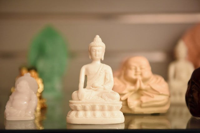 White Buddha figurine surrounded by various other Buddha figurines