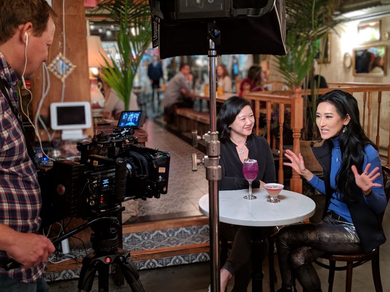 Pearl River Mart President Joanne Kwong with TV personality Kelly Choi enjoying drinks at Chelsea Market with a camera films them