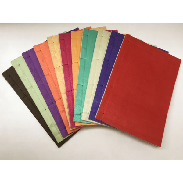 An array of silk covered bound journals. Their individual colors are: Brown, lime, purple, orange, yellow, red, magenta, green, yellow green, and blue