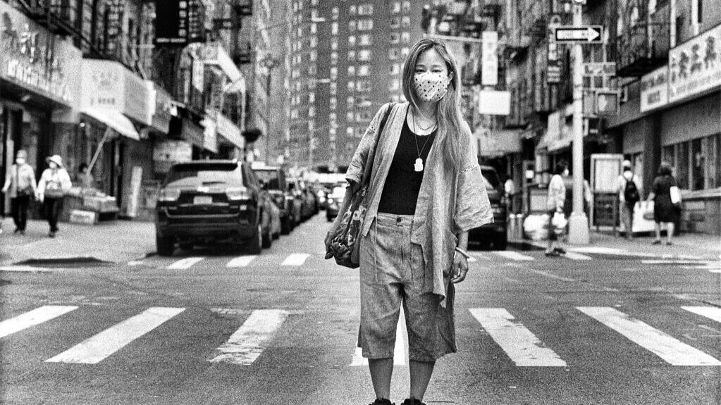 Woman with mask standing in street of NYC Chinatown